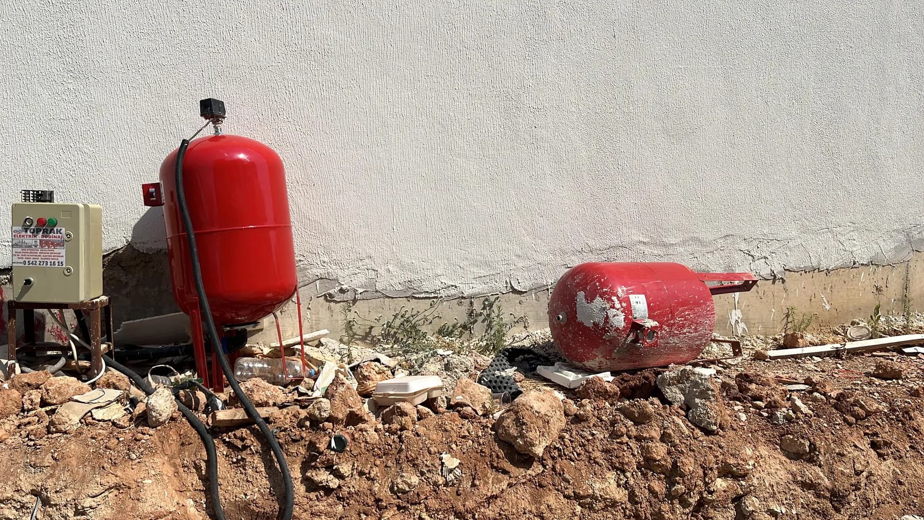 Dış mekânda dik basınç tankı ve yanında sökülmüş tank